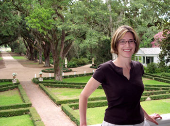 The author poses on the second-story porch of the Rosedown Plantation home with the front gardens in the background.