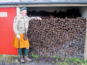 Brendan Rohan poses next to piles of peat at The Corcreggan Mill in Dunfanaghy, where he owns and operates a hostel and B&B.