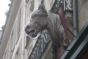 A horsehead sticking out from a building, denoting a horsemeat shop.