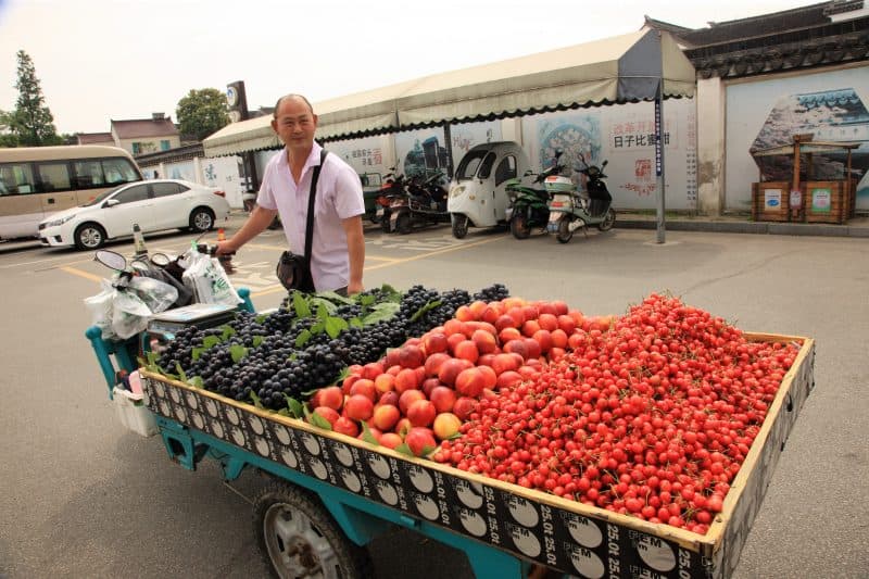 A friendly fruit vendor with his mobile stand in Suzhou.