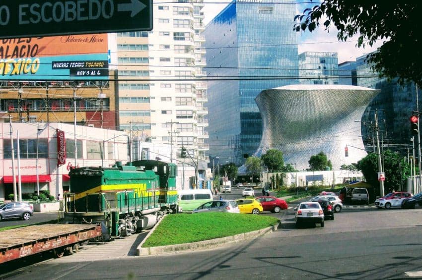 Incongruous sight - iconic Soumaya Museum, cars and diesel locomotive - Mexico City.