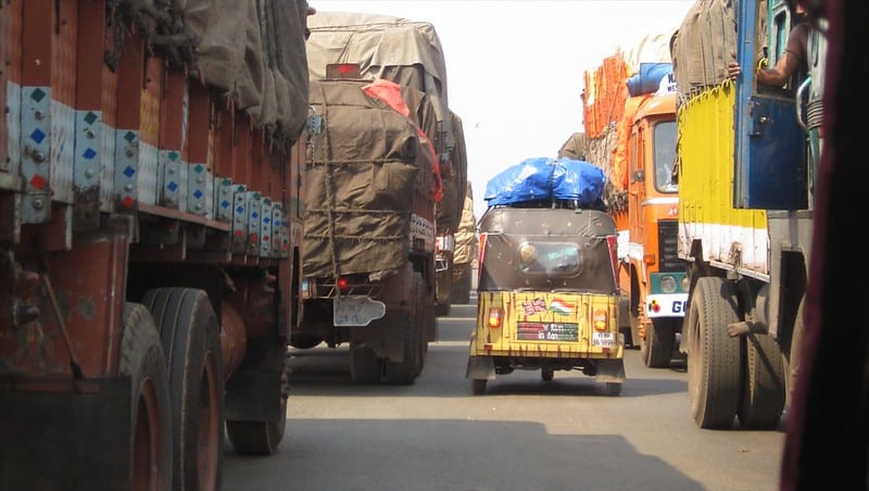 A rickshaw squeezing between trucks at the Rickshaw Run