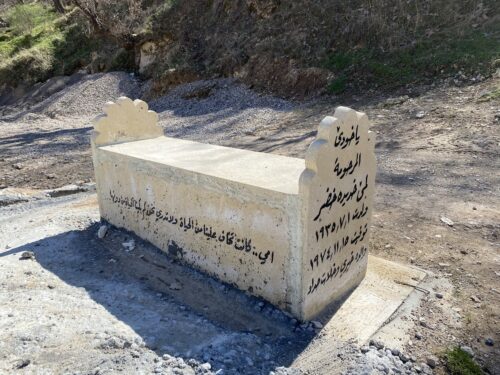 A Yazidi tomb stands in the open space behind a home, where inscriptions in Kurdish detail the legacy of the deceased.
