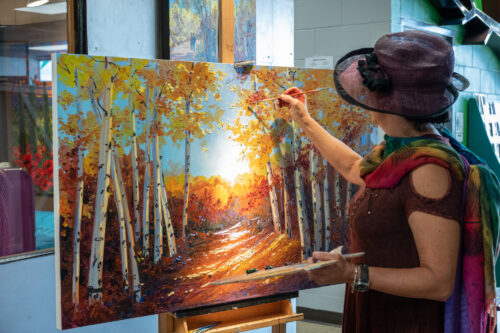 Inside the Artisan Forge Studios, artist Wendy Schaefer-Miles works on a fall landscape.