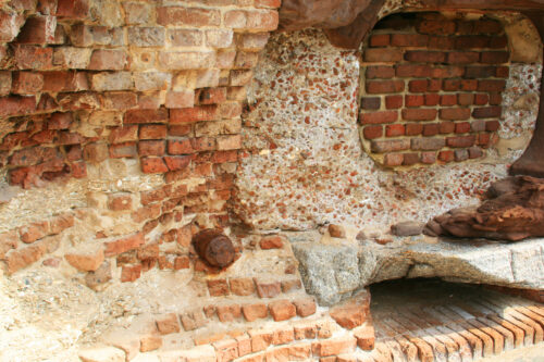 A rusted artillery shell lay embedded in the crumbling wall