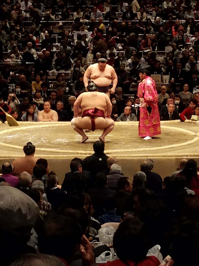 Wrestlers about to begin their bout with the referee (gyoji) standing by