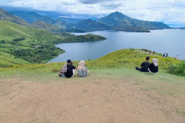 People relax on the grassy hill overlooking the lake at Holbung Hill