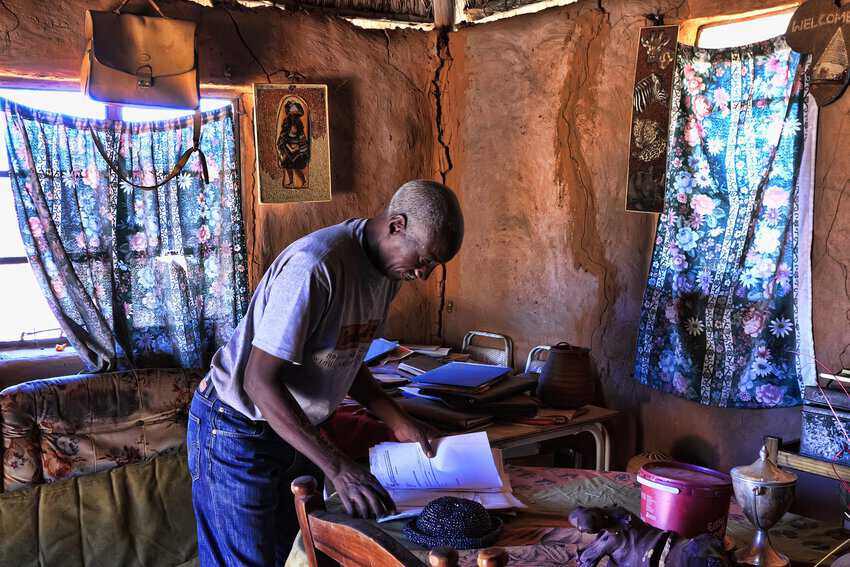 Ndlovu rummaging through his paper, looking for an article published about his work at Harvard.