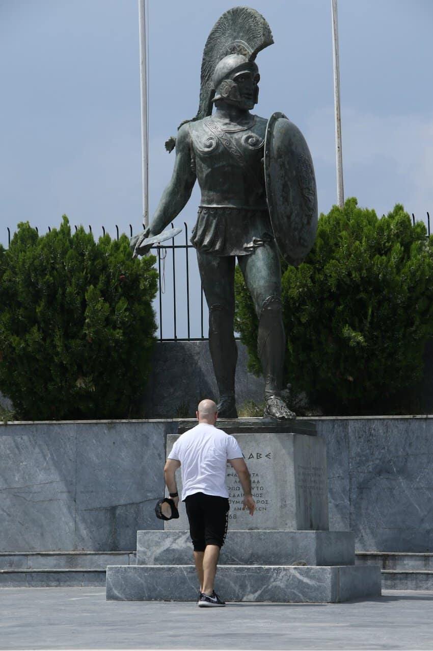 a man walking up stairs in front of a statue of a warrior