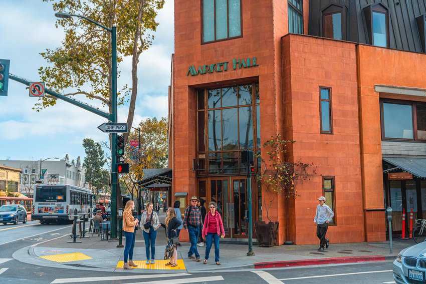 Rockridge Neighborhood, a vibrant community known for its charming shops and eateries, featuring people standing on the corner in front of Market Hall.